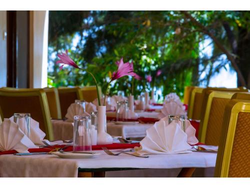 a table with white tables with pink flowers on them at Wigot Gardens Hotel in Kisumu