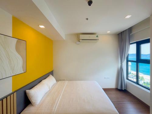 a bedroom with a white bed and a yellow wall at Tony Apartment -FLC Sea Tower Quy Nhon in Quy Nhon