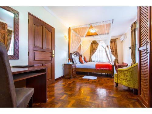 a bedroom with a bed with a desk and a window at Wigot Gardens Hotel in Kisumu