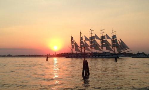 a tall ship sitting in the water at sunset at Hotel Russo Palace in Venice-Lido