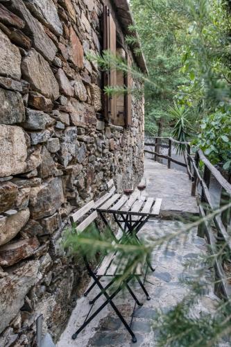 a wooden bench sitting next to a stone building at Μilia Mountain retreat in Vlátos