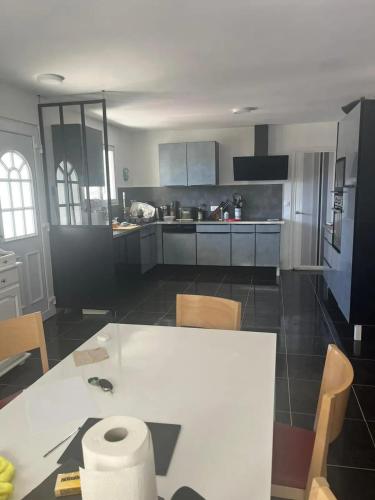 une cuisine avec une table blanche et un comptoir blanc dans l'établissement Maison charmante à Marseillan avec grand jardin et terrasse, à Marseillan