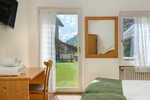 Schlafzimmer mit einem Bett, einem Schreibtisch und einem Fenster in der Unterkunft Albergo Alla Costa in Ledro