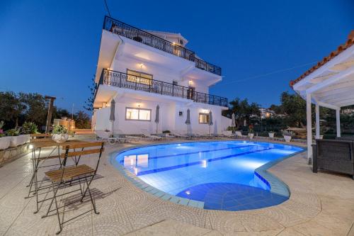 a villa with a swimming pool in front of a house at Denise Studios and Apartments in Argasi