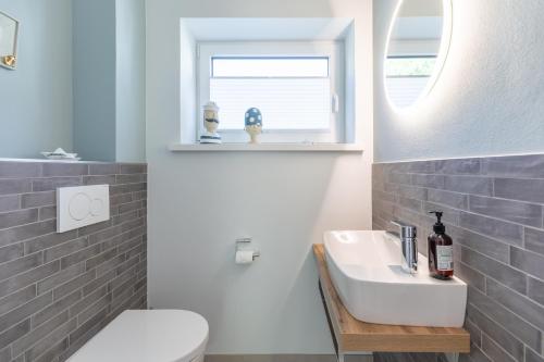 une salle de bain avec un lavabo et des toilettes et une fenêtre dans l'établissement Hus Veer, à Sankt Peter-Ording
