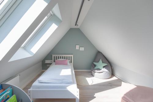 une petite chambre mansardée avec un lit et des livres dans l'établissement Hus Veer, à Sankt Peter-Ording