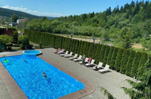 a swimming pool with chairs and people sitting around it at СПА-Готель "RESPECT" in Skhidnitsa