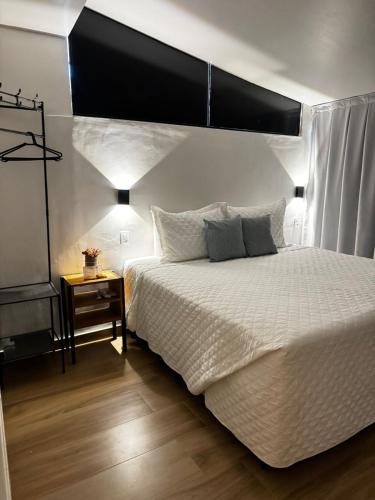 1 dormitorio con 1 cama blanca grande y cabecero negro en Suítes Viver Arraial do Cabo, en Arraial do Cabo