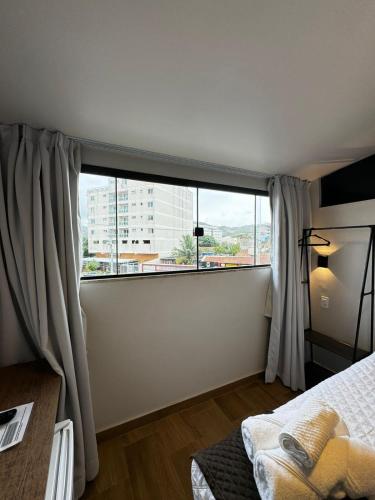 1 dormitorio con ventana grande y cama en Suítes Viver Arraial do Cabo, en Arraial do Cabo