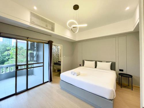 a bedroom with a white bed and a balcony at Boss Mansion in Bangkok