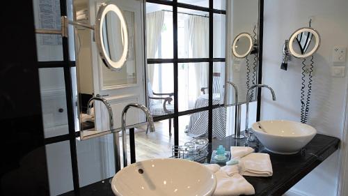 a bathroom with two sinks and a mirror at Hotel les Vergers de Saint Paul in Saint Paul de Vence