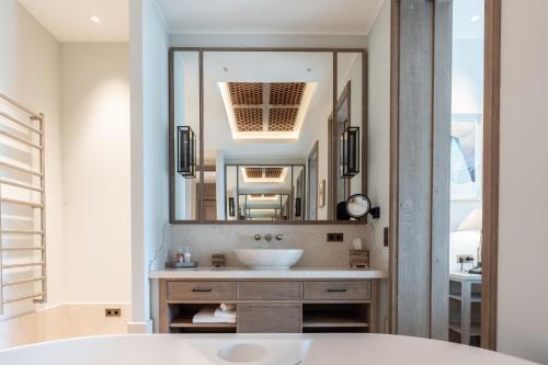 La salle de bains est pourvue d'un lavabo et d'un grand miroir. dans l'établissement Coquillade Provence, à Gargas