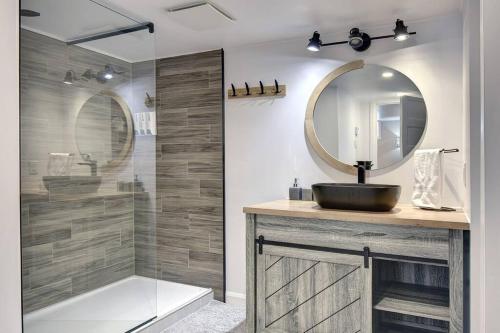 a bathroom with a sink and a mirror and a shower at Chalet Émond - Petit Train du Nord, Golf et ski in Mont-Tremblant