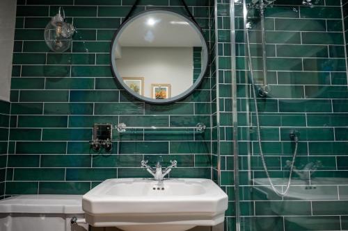 a green tiled bathroom with a sink and a mirror at Ethorpe Hotel by Chef & Brewer Collection in Gerrards Cross