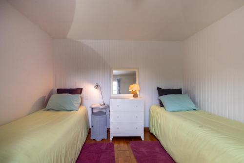 een slaapkamer met 2 bedden en een dressoir met een spiegel bij Les Sapins in Rochefort-en-Terre