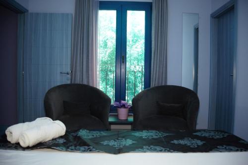 ジュニエにあるHOtello guest suitesのベッドルーム1室(椅子2脚、ベッド1台、窓付)