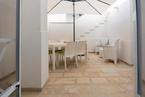 a dining room with a table and chairs and an umbrella at Seasons Home San Foca in San Foca
