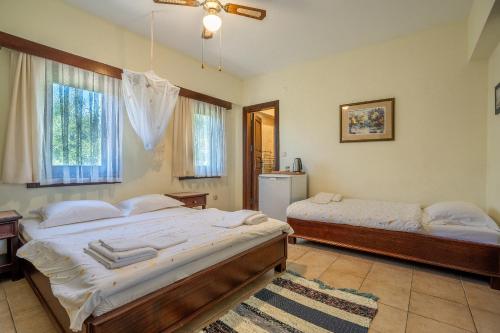 two beds in a bedroom with two windows at Bagbadem Tatil Çiftliği in Bozcaada