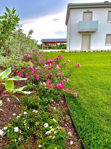 a garden with pink flowers in front of a house at Appartamento a Quarto D Altino - La Rosa del Sile in Quarto dʼAltino