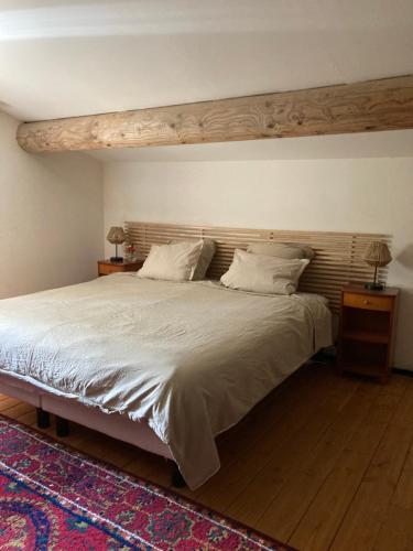 une chambre avec un grand lit avec une tête de lit en bois dans l'établissement Gîte Bergerie des Mougères, à Galargues