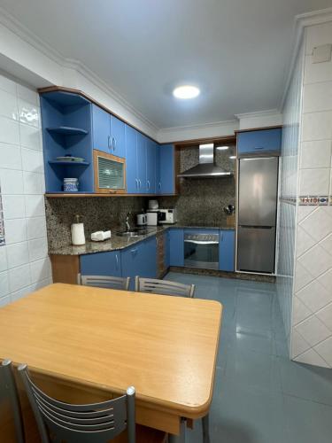 a kitchen with blue cabinets and a wooden table at Camiño da Vila in Redondela
