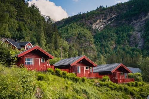 a row of red cottages in a mountain at Vinje Camping in Geiranger