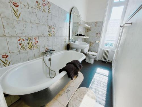 une salle de bain avec une baignoire, des toilettes et un lavabo dans l'établissement Appartement lumineux en centre-ville avec parking, à La Rochelle