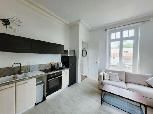 une cuisine et un salon avec un canapé et une table dans l'établissement Appartement lumineux en centre-ville avec parking, à La Rochelle