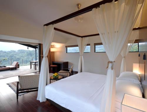 a bedroom with a canopy bed and a living room at Dharana at Shillim All Inclusive Luxury Wellness Retreat in Lonavala