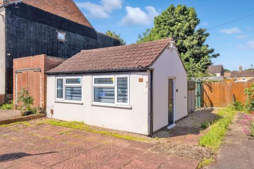 a small white shed with a window at Small and cosy entire House in Peterborough in Peterborough
