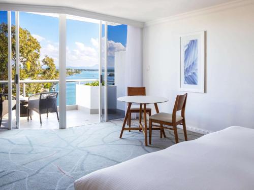 a bedroom with a bed and a table and chairs at Sofitel Noosa Pacific Resort in Noosa Heads