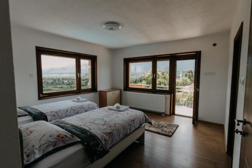 a bedroom with two beds and two large windows at Villa Lamija in Bihać
