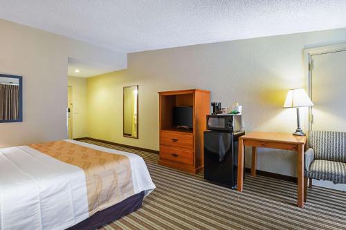 Cette chambre comprend un lit, une chaise et un bureau. dans l'établissement Quality Inn & Suites NRG Park - Medical Center, à Houston
