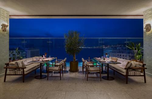 Swissotel Buyuk Efes Izmir في إزمير: مطعم بطاولات وكراسي وجدار ازرق