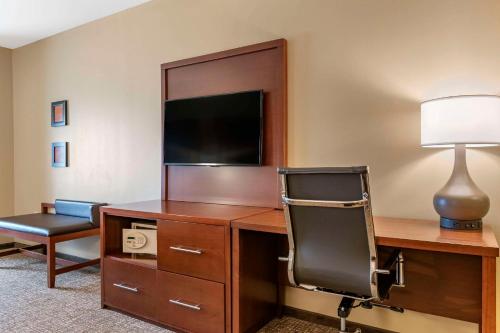 a room with a desk with a chair and a television at Comfort Suites Manheim - Lancaster in Manheim