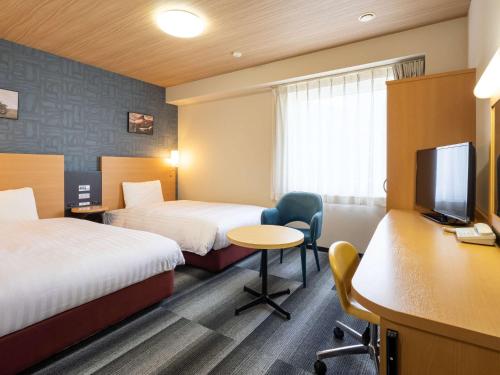 um quarto de hotel com duas camas e uma secretária e uma televisão em Comfort Hotel Kariya em Kariya