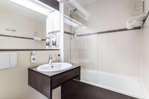 a white bathroom with a sink and a shower at Comfort Hotel Orleans Saran in Saran