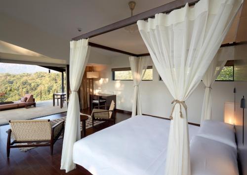 a bedroom with a bed and a living room at Dharana at Shillim All Inclusive Luxury Wellness Retreat in Lonavala
