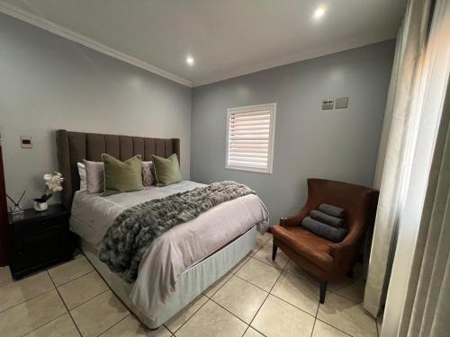 a bedroom with a large bed and a chair at Bluestream Villas in Pretoria