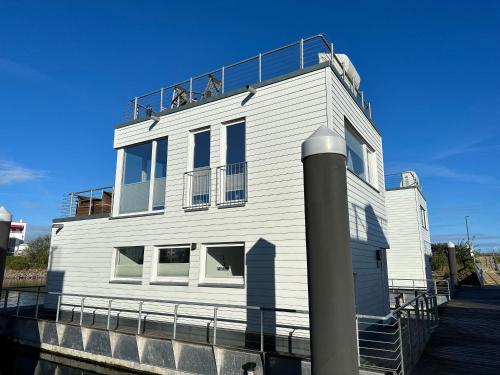 a white building with a balcony on top of it at Schwimmendes Haus - An Bord Zwei in Kappeln