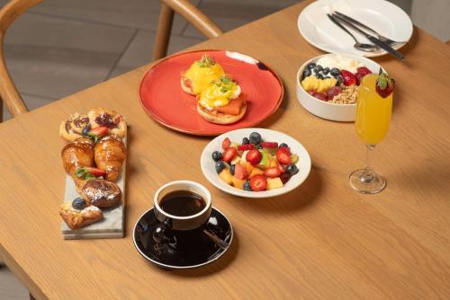 a table with plates of breakfast food and a cup of coffee at Radisson RED Hotel Johannesburg Rosebank in Johannesburg