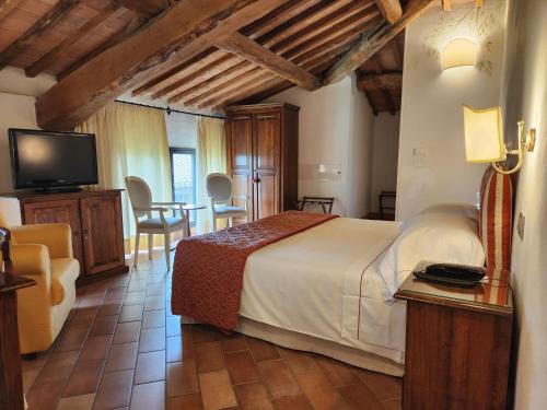 a bedroom with a bed and a tv and a table at Villa Curina Resort in Castelnuovo Berardenga