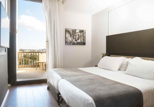 a bedroom with a large bed and a balcony at Cassia Hotel Jerusalem in Jerusalem