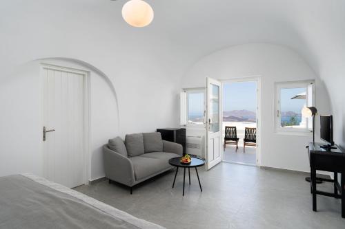 a bedroom with a bed and a chair and a table at Petit Palace Suites in Fira