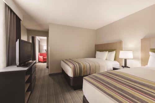 a hotel room with two beds and a flat screen tv at Country Inn & Suites by Radisson, Bakersfield, CA in Bakersfield