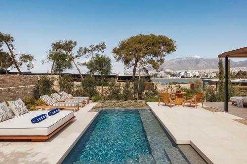 un patio trasero con una piscina con sillas y una mesa en One&Only Aesthesis en Atenas