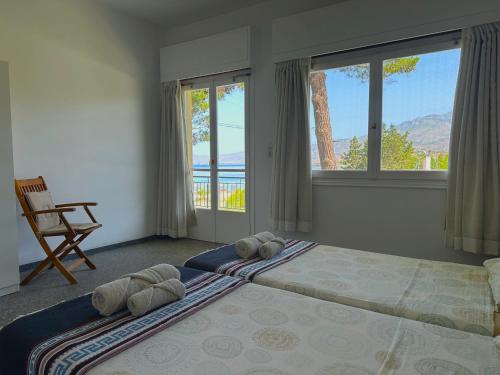 a bedroom with two beds and a chair and windows at Bouros Seaview Farm in Karistos