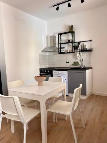 a kitchen with a white table and chairs in a room at BISCOTTAI Port Apartments in Trapani