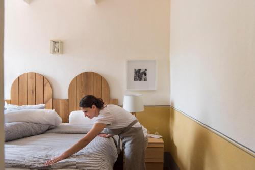a man is making a bed in a hotel room at Bioagriturismo il cerreto in Pomarance