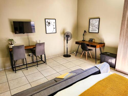 a room with a bed and a desk and a table at No Loadshedding Fast WiFi Lux Apartment in Johannesburg